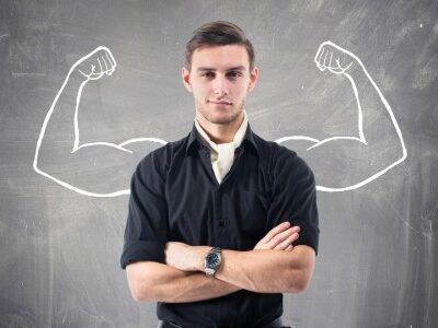Man standing in front of chalkboard with strong muscles flexing drawn in behind him