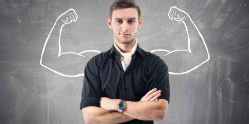 Man standing in front of chalkboard with strong muscles flexing drawn in behind him