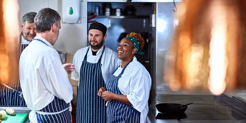 Four chefs chatting in commercial kitchen